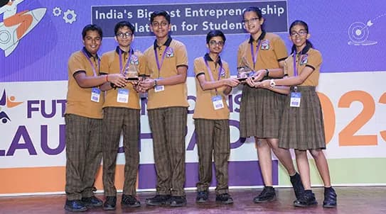 Five students in school uniform holding their trophies on the Future Unicorns Launchpad stage