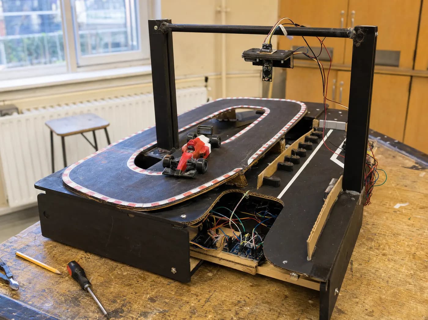 Kabir, with F1 Racing. A tabletop Formula 1 simulation: robotic race car on a looping track with a sensor gantry and pit lane