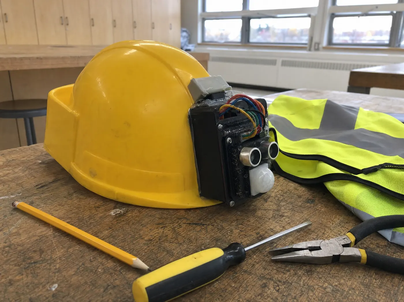 Anika, with HeadSafe Pro. A yellow hard hat with a sensor module beside a high-visibility vest