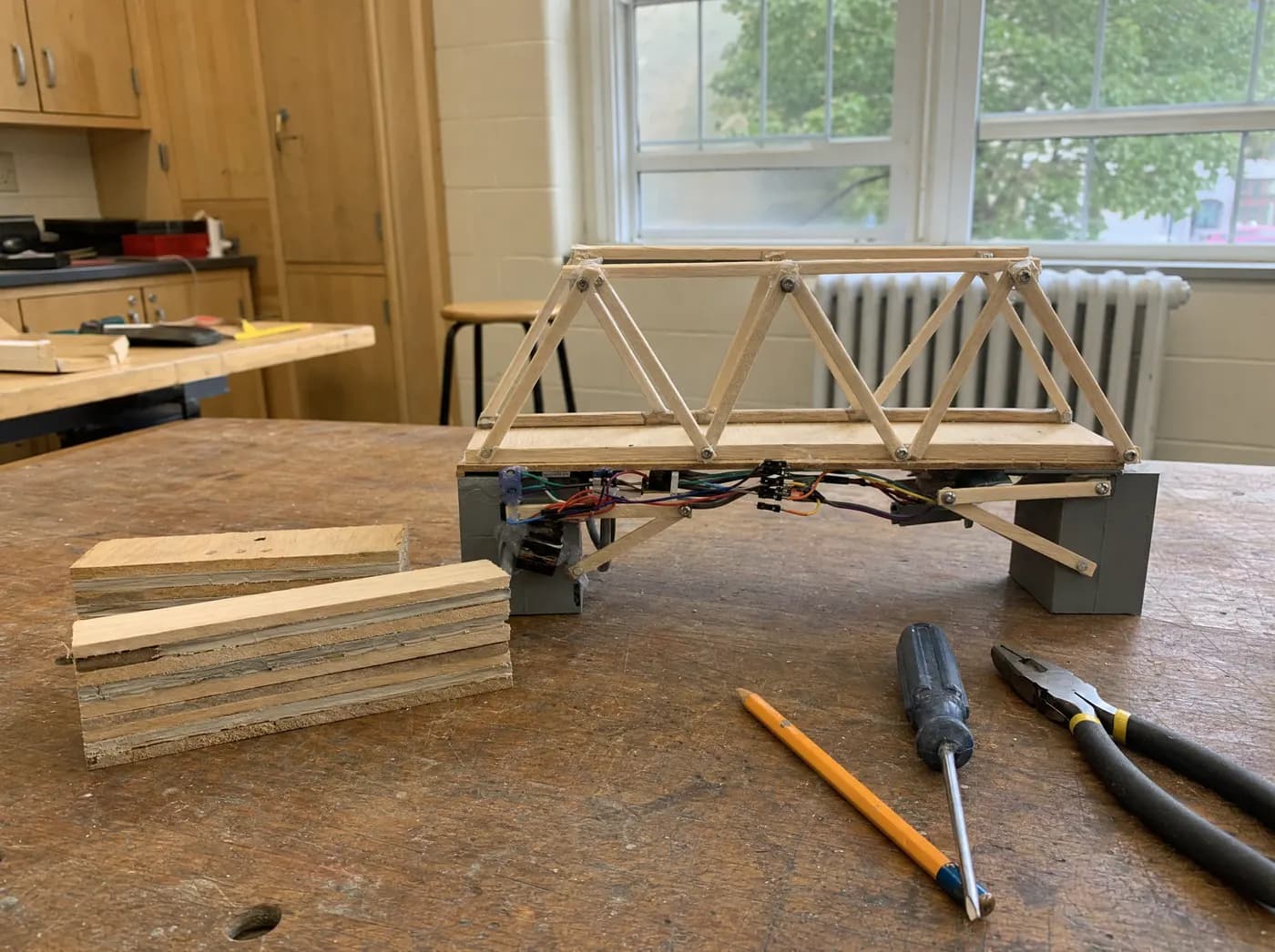 Vivaan, with STEEL ROOT. Layered engineered-timber beam samples beside a small truss bridge model
